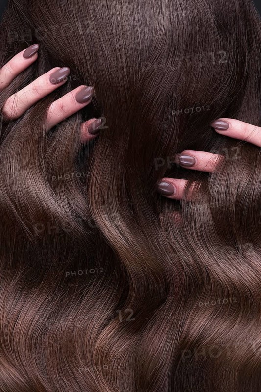 A closeup view of a bunch of shiny curls brown hair