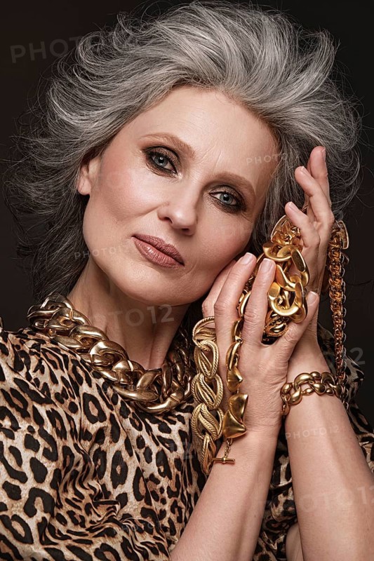 Portrait of a beautiful elderly woman in a leopard blouse with classic makeup and gray hair