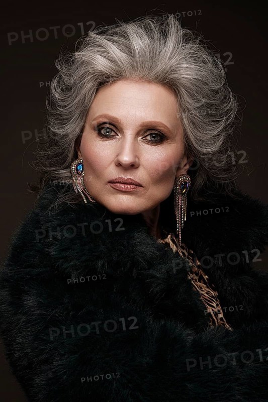 Portrait of a beautiful elderly woman in a leopard blouse and fur coat with classic makeup and gray hair