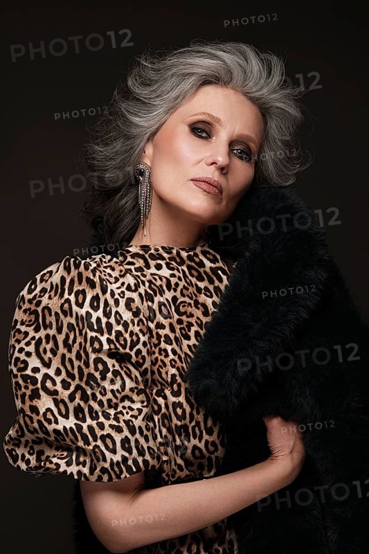 Portrait of a beautiful elderly woman in a leopard blouse and fur coat with classic makeup and gray hair