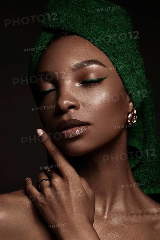 Beautiful black woman with a green towel on her head and classic make-up. Beauty face. Photo taken in the studio