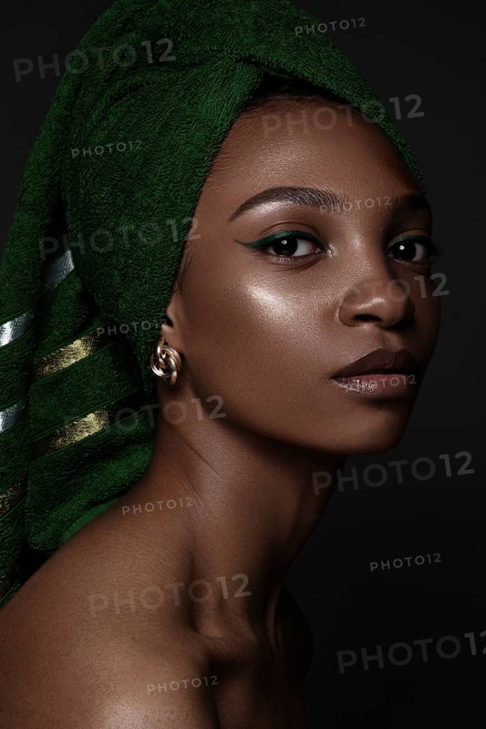 Beautiful black woman with a green towel on her head and classic make-up. Beauty face. Photo taken in the studio
