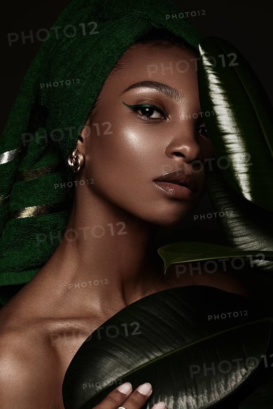 Beautiful black woman with a green towel on her head and classic make-up. Beauty face. Photo taken in the studio
