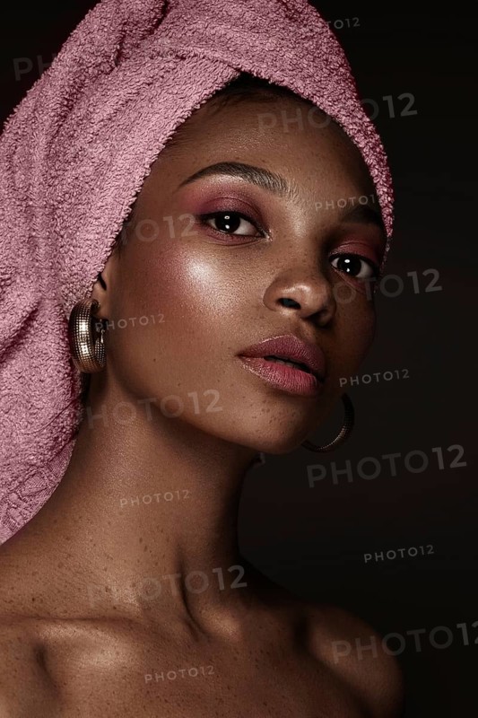 Beautiful black woman with a pink towel on her head and classic makeup. Beauty face. Photo taken in the studio