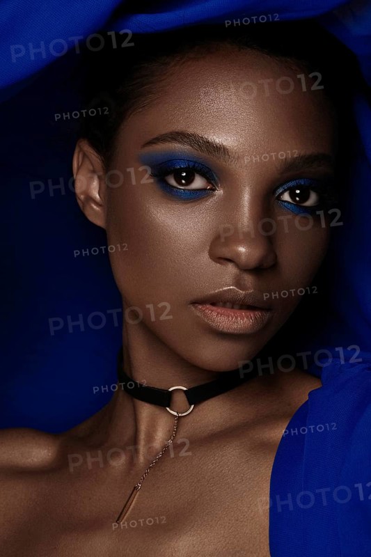 Beautiful black woman with blue fabric and classic art make-up. Beauty face. Photo taken in the studio