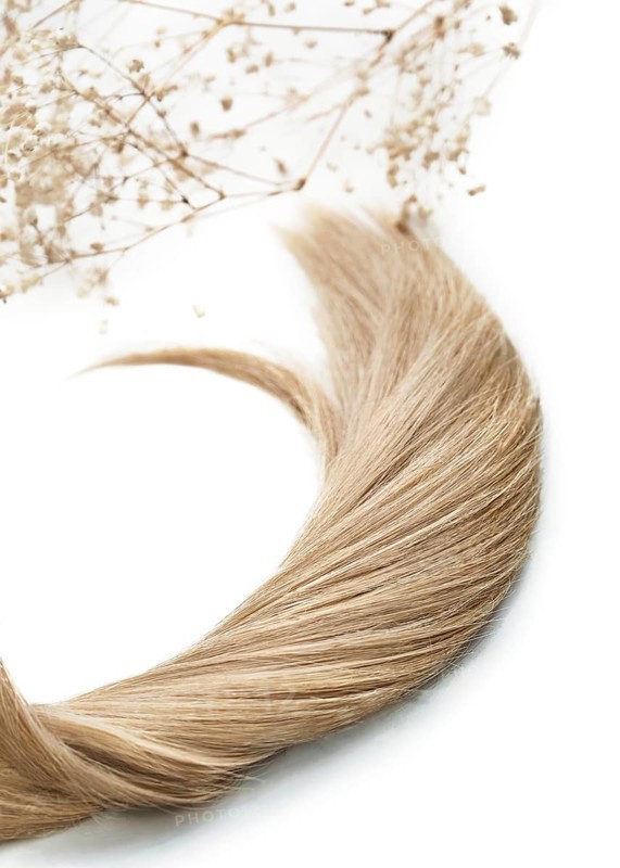 A strand of blond hair on a white background. Close-up