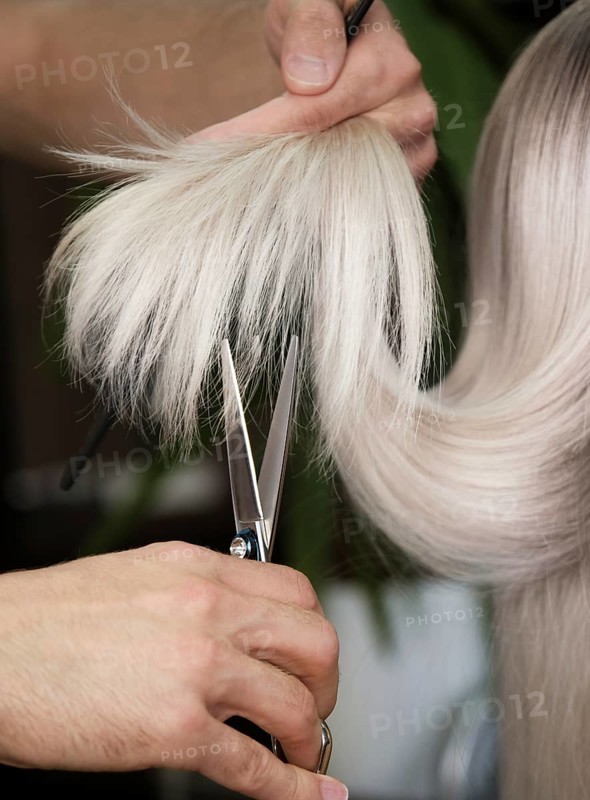 Young woman in a hairdressing salon dyes her hair blond and cuts hair