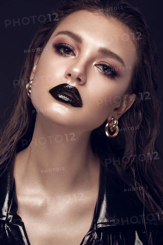 Beautiful girl with black creative art make-up and gold accessories. Beauty face. Photos shot in studio