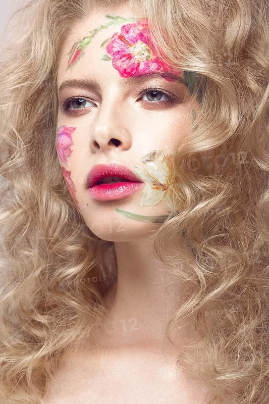 Beautiful blond girl with tresses and a floral pattern on the face. Beauty flowers. Portrait shot in studio