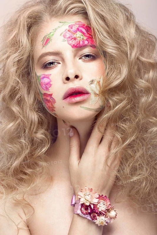 Beautiful blond girl with tresses and a floral pattern on the face. Beauty flowers. Portrait shot in studio