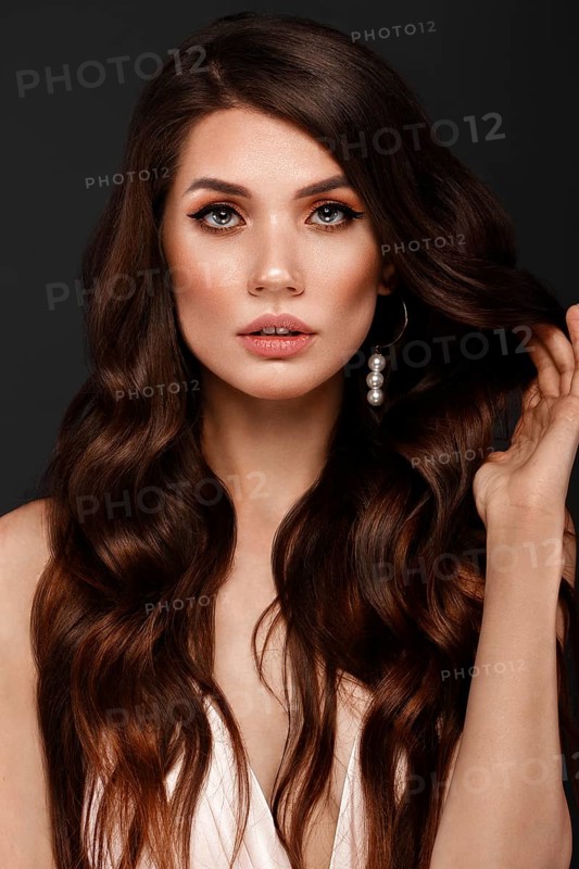 Beautiful brunette woman with curls and classic make-up. Beauty face. Photo taken in studio