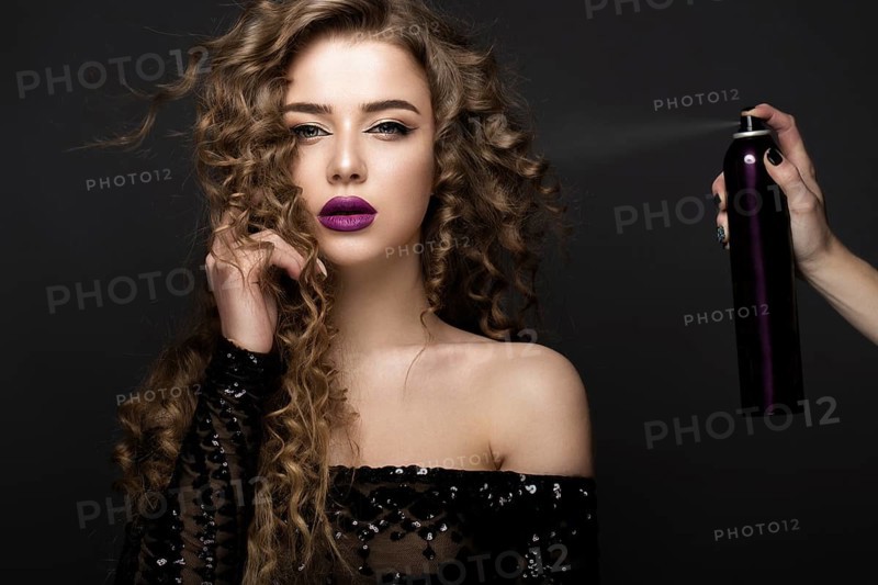 Beautiful brunette model with classic makeup and bottle of hair products. beauty face. Portrait shot in the studio