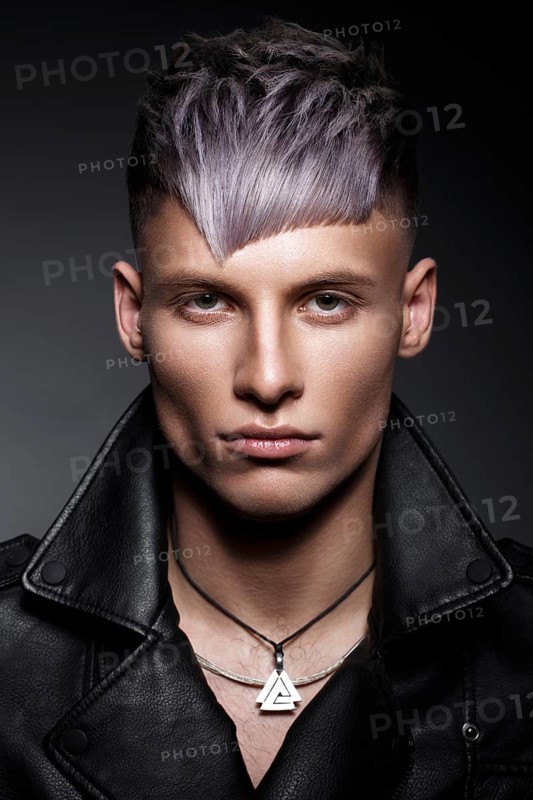 Young man with purple hair and creative makeup and hair. Photo taken in the studio