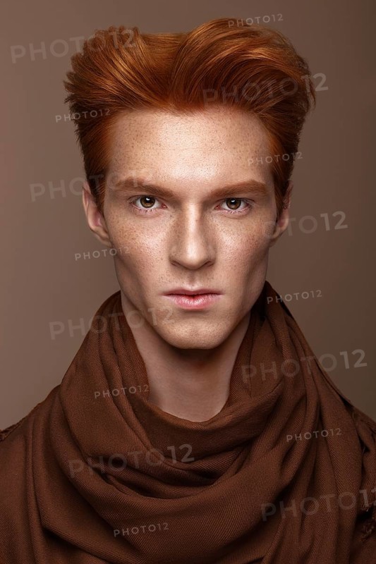 Young man with red hair and creative make up and hair. Photo taken in the studio