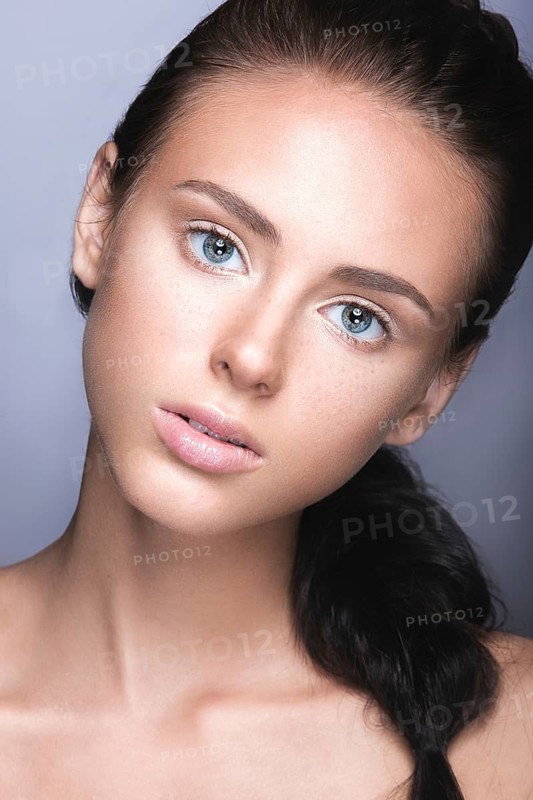 Beautiful young girl with a light natural make-up. Beauty face. Picture taken in the studio on a grey background
