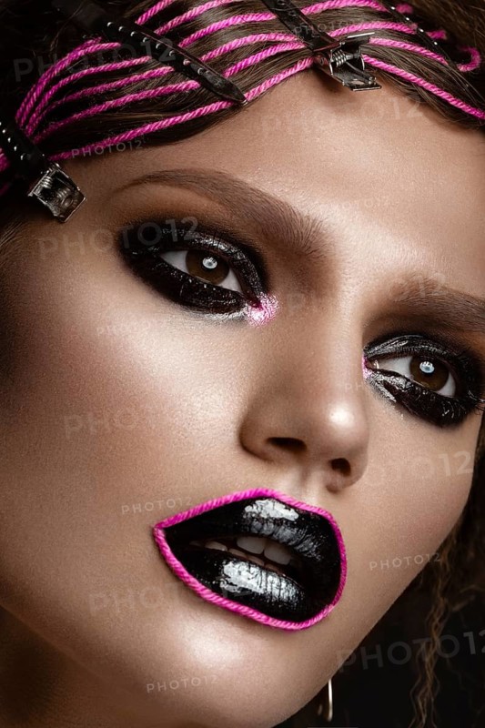 A beautiful girl with a black creative make-up and a pink thread on her lips. Beauty face. Photos shot in studio