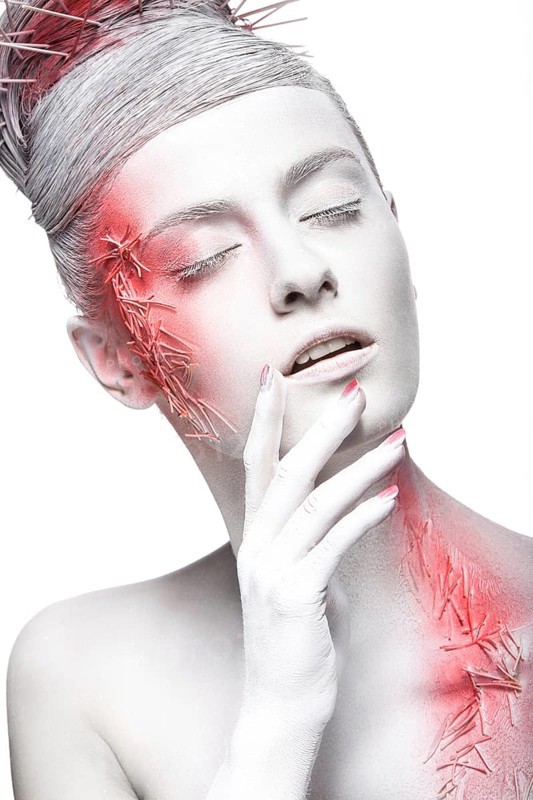 Art fashion girl with white skin and red paint on the face. Creative art beauty. Picture taken in the studio on a black background