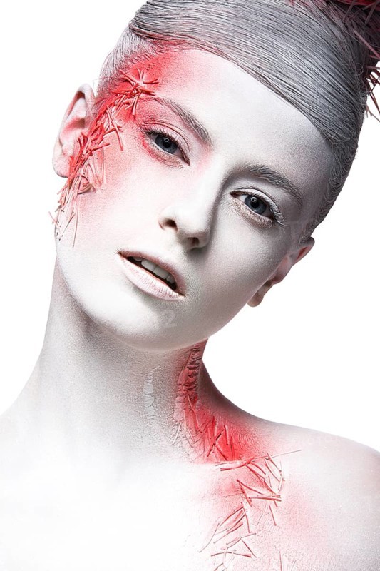 Art fashion girl with white skin and red paint on the face. Creative art beauty. Picture taken in the studio on a black background