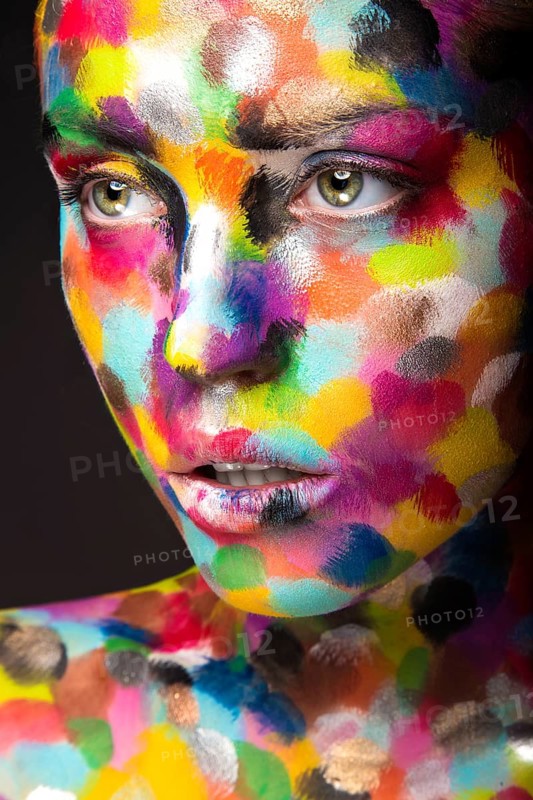 Girl with colored face painted. Art beauty image. Picture taken in the studio on a black background