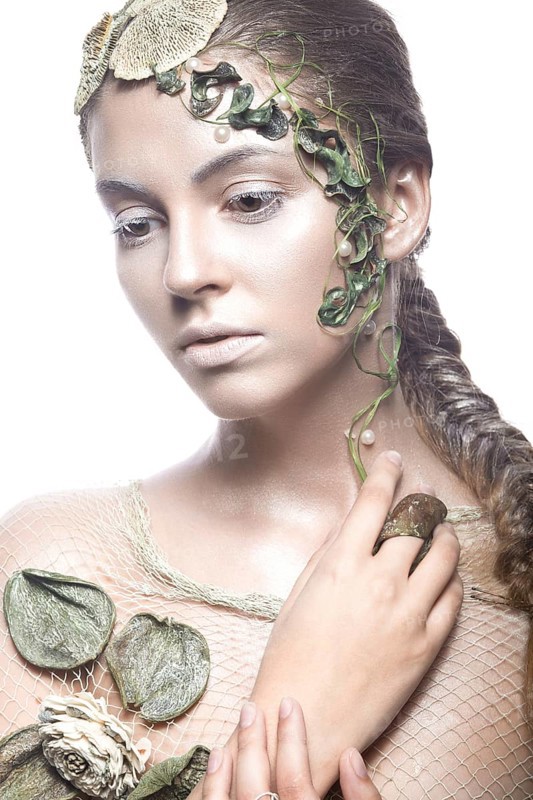 Beautiful fashionable girl in image of sea fairies with shells and algae on the face. Art beauty face. Picture taken in the studio