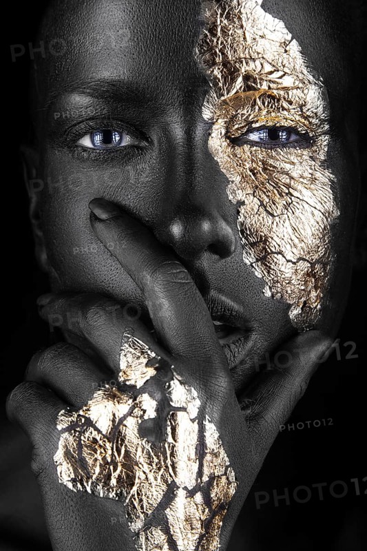 Fashion portrait of a dark-skinned girl with gold make-up.Beauty face. Picture taken in the studio on a black background
