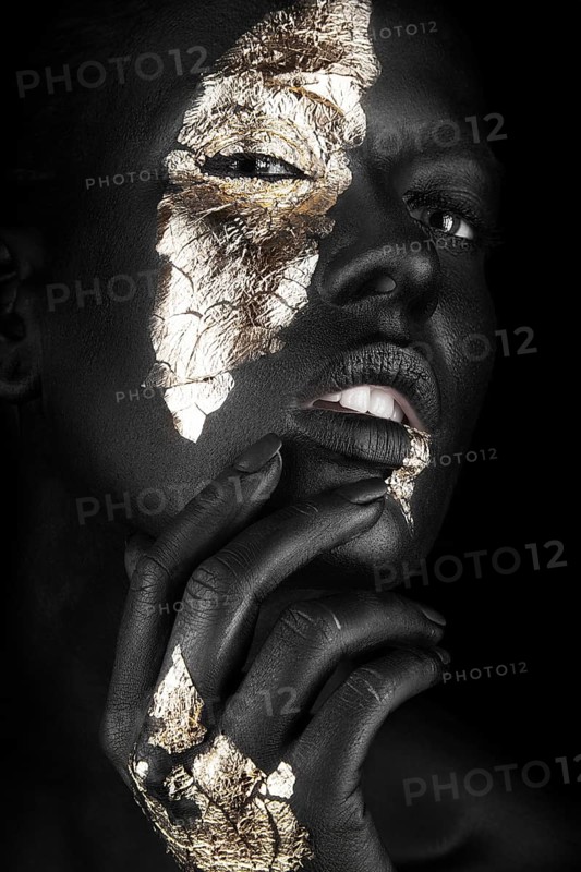 Fashion portrait of a dark-skinned girl with gold make-up.Beauty face. Picture taken in the studio on a black background