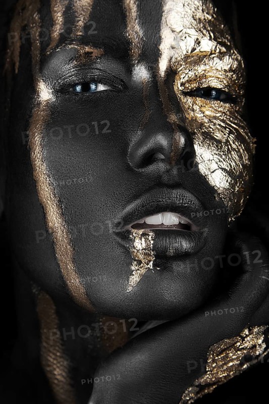 Fashion portrait of a dark-skinned girl with gold make-up.Beauty face. Picture taken in the studio on a black background