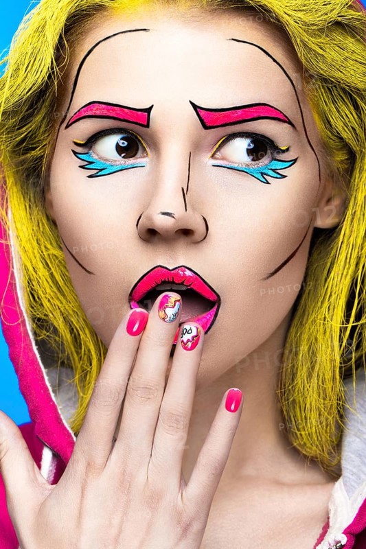 Photo of surprised young woman with professional comic pop art make-up and design manicure. Creative beauty style and nails. Photos shot in studio