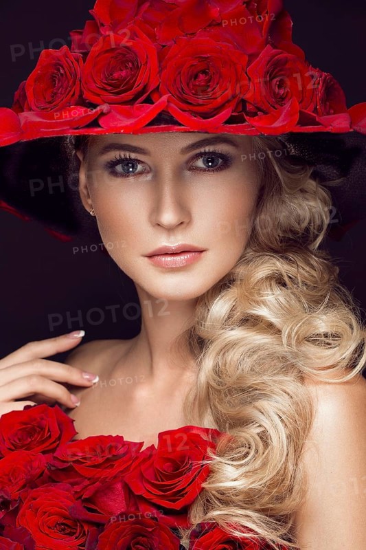 Beautiful blond girl in a dress and hat with roses