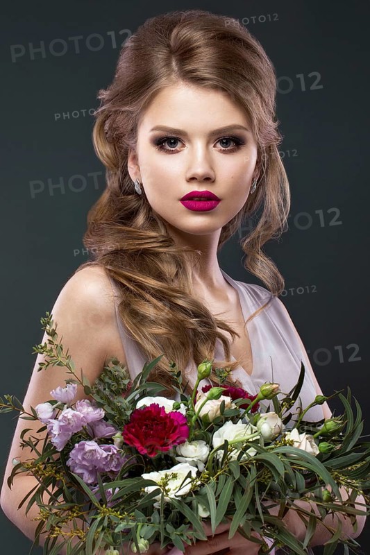 Portrait of a beautiful woman in the image of the bride with flowers in her hands. Picture taken in the studio. Beauty face and Hairstyle
