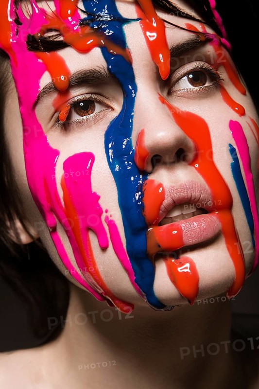 Portrait of a beautiful Girl with red paint on her face. Photo shot in the Studio on a black background