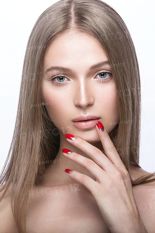Beautiful young girl with a bright make-up and red nails. Picture taken in the studio on a white background