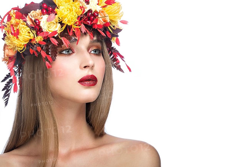 Beautiful girl with bright autumn wreath of leaves and flowers. Beauty face. Picture taken in the studio on a white background