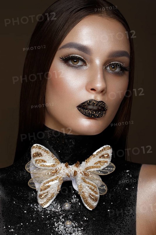 Beautiful girl with black creative art make-up and gold accessories. Beauty face. Photos shot in studio