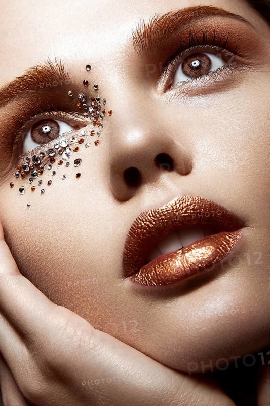 Beautiful girl with a gentle make-up and crystals on the face. Close-up portrait. Beauty face. Picture taken in the studio