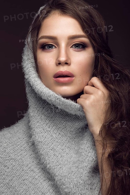 Beautiful young girl with gentle make-up in warm sweater and long straight hair. Beauty face. Studio portrait