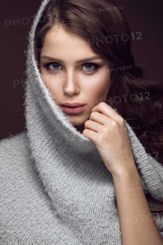 Beautiful young girl with gentle make-up in warm sweater and long straight hair. Beauty face. Studio portrait