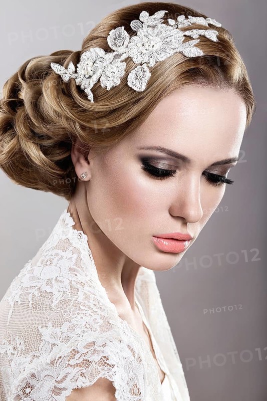 Portrait of a beautiful blonde woman in the image of the bride with flowers in her hair. Picture taken in the studio on a blue background