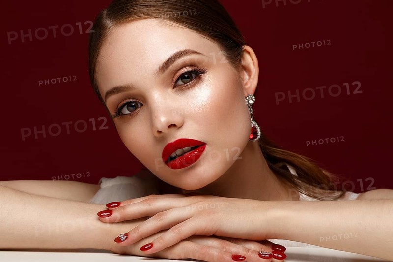Beautiful girl in red dress with classic make-up and red manicure. Beauty face. Photo taken in the studio