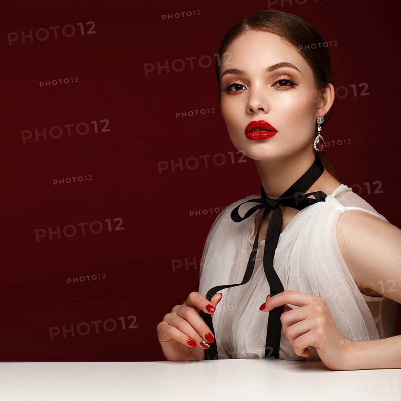 Beautiful girl in white dress with classic make-up and red manicure. Beauty face. Photo taken in the studio
