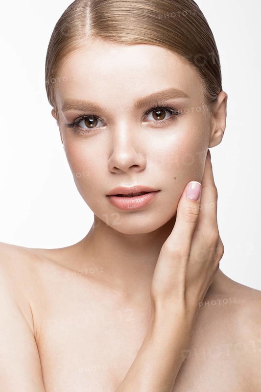Beautiful young girl with a light natural make-up and French manicure. Beauty face. Picture taken in the studio on a white background