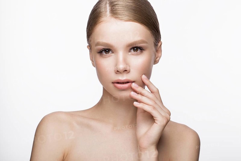 Beautiful young girl with a light natural make-up and French manicure. Beauty face. Picture taken in the studio on a white background