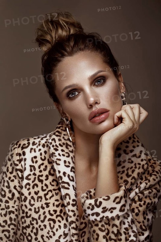 Beautiful sexy woman in a leopard coat and earrings