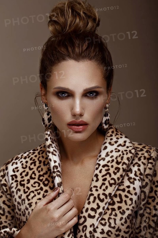 Beautiful sexy woman in a leopard coat and earrings