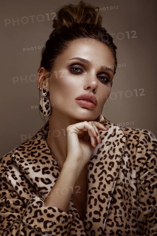 Beautiful sexy woman in a leopard coat and earrings