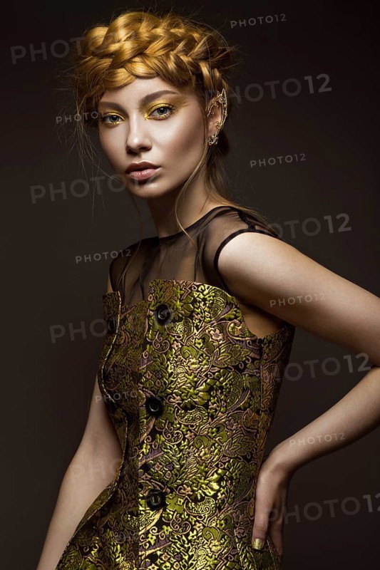 Beautiful girl in a gold dress with creative makeup and braids on her head. The beauty of the face. Photos shot in the studio