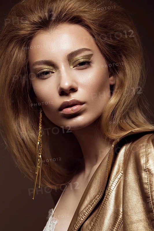 Beautiful girl in a gold dress with creative makeup and hair. The beauty of the face. Photos shot in the studio