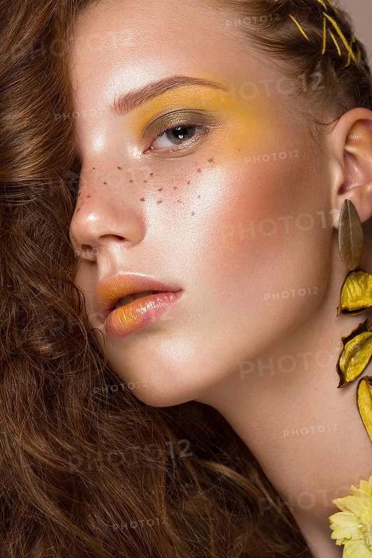 Portrait of beautiful red-haired girl with brightly colored art makeup and curls. Beauty face. Photo taken in the studio