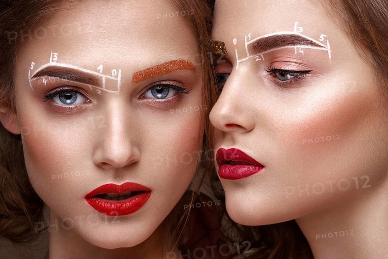 Two girls are twin sisters with an unusual eyebrow makeup. Beauty face. Photo taken in the studio