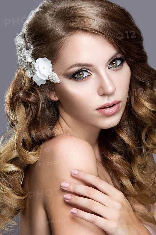 Portrait of a beautiful woman in the image of the bride with flowers in her hair. Picture taken in the studio on a grey background